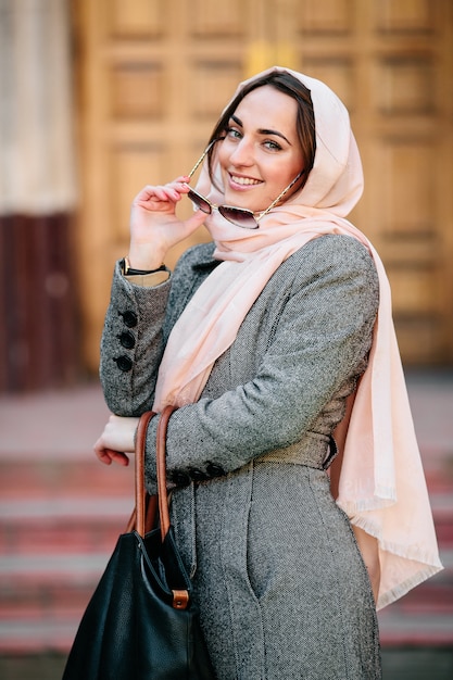 Mulher jovem e bonita com um casaco e uma bolsa posando