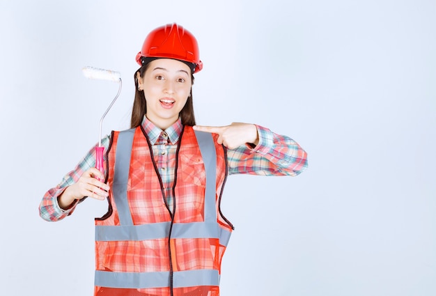 Mulher jovem e bonita com um rolo de pintura para pintar o reparo da parede.