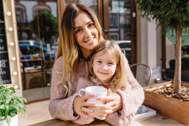 Mulher jovem e bonita com uma filha linda vestida com suéteres quentes na rua