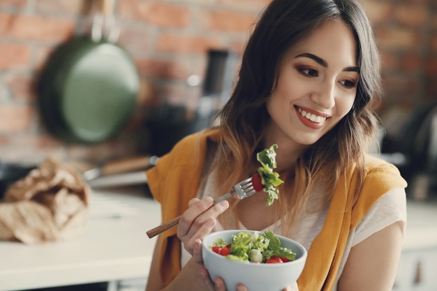 Mulher jovem e bonita comendo uma salada saudável