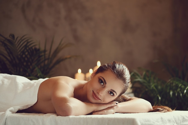 Mulher jovem e bonita deitada e esperando sua massagem. Conceito de spa