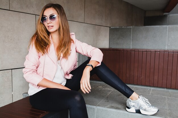 Mulher jovem e bonita elegante hipster em jaqueta de couro rosa