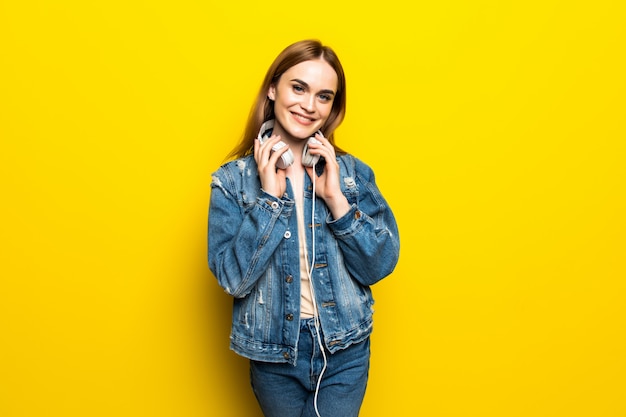 Foto grátis mulher jovem e bonita em fones de ouvido, ouvindo música e dançando na parede amarela