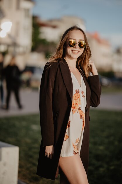 Mulher jovem e bonita em óculos de sol na cidade ao pôr do sol