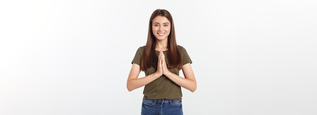 Mulher jovem e bonita em roupas casuais juntos de mãos dadas e rezando isolado no branco