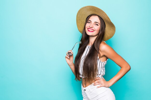 Mulher jovem e bonita em shorts jeans e camisa laranja, posando com os braços levantados. no fundo verde-azulado.