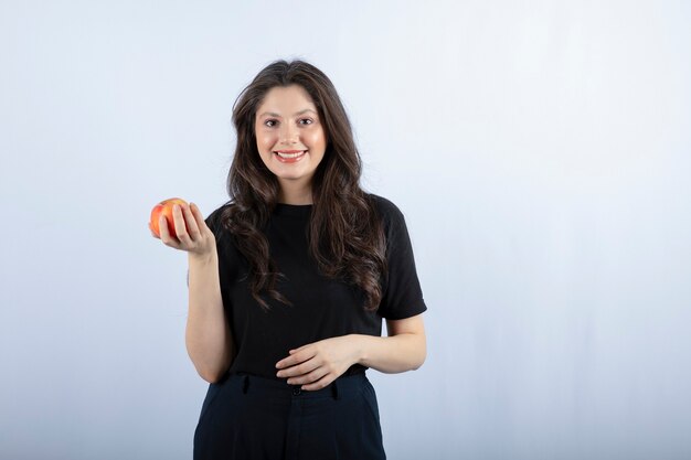 mulher jovem e bonita em top preto posando com maçã fresca.