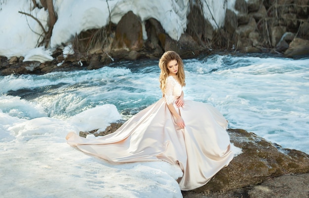 Mulher jovem e bonita em um vestido de noiva à beira do rio