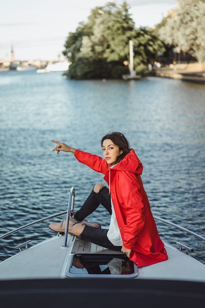 mulher jovem e bonita em uma capa de chuva vermelha monta um iate privado. Estocolmo, Suécia