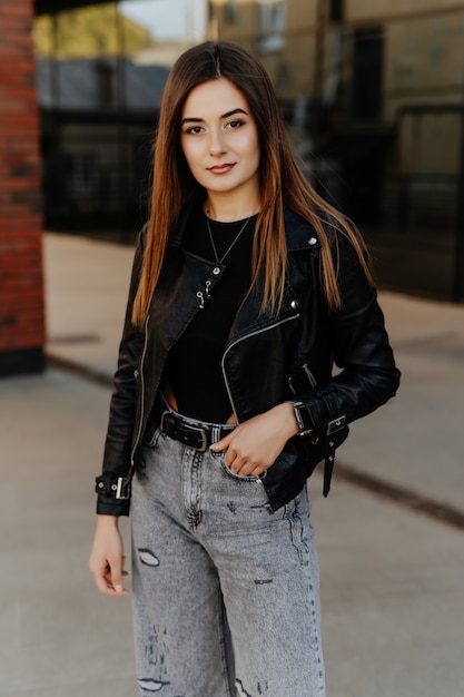 Mulher jovem e bonita em uma jaqueta de couro preta posando na rua