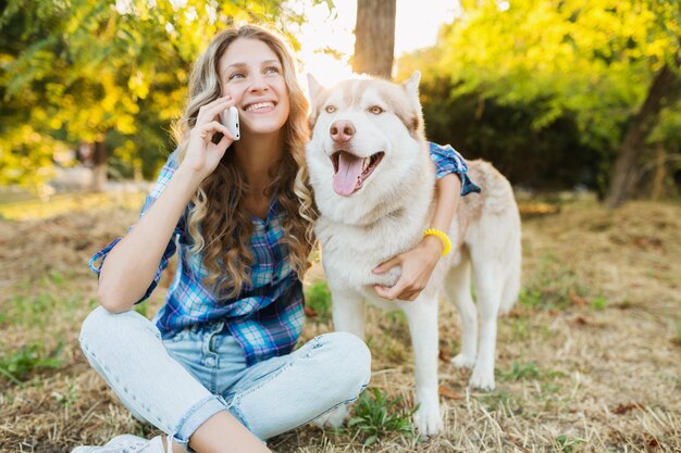 Mulher jovem e bonita engraçada brincando com cães de raça husky no parque em um dia ensolarado de verão