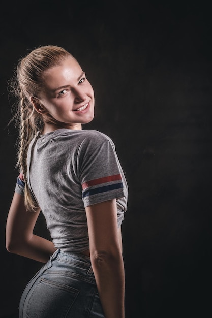 Mulher jovem e bonita está posando para fotógrafo no estúdio fotográfico escuro.