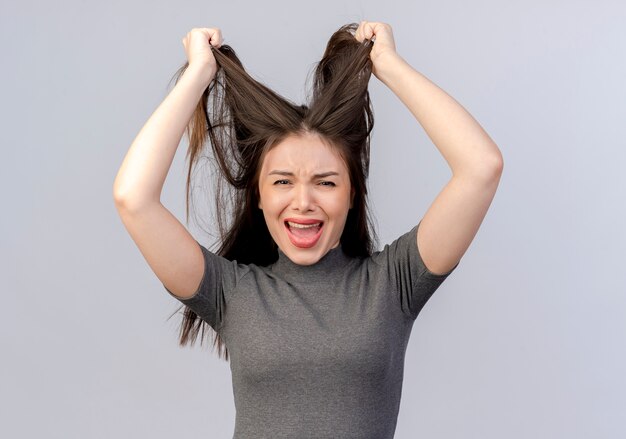 Mulher jovem e bonita estressada puxando o cabelo dela, isolado no fundo branco