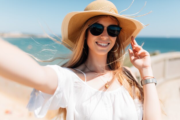 Mulher jovem e bonita fazendo selfie na praia no oceano