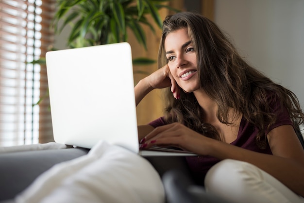 Mulher jovem e bonita feliz com o laptop em casa