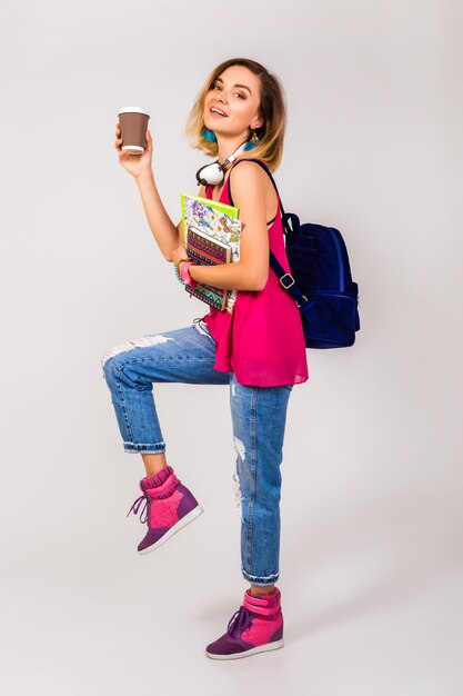 Mulher jovem e bonita hippie, sapatos rosa e top segurando livros e tomando café