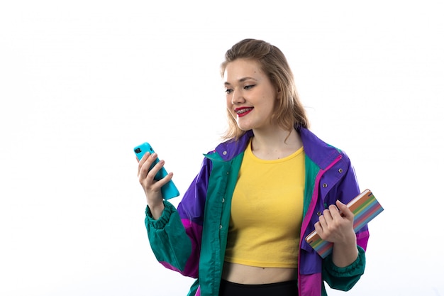 Mulher jovem e bonita jaqueta colorida usando smartphone e segurando o livro
