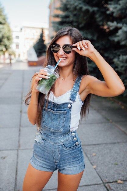 Mulher jovem e bonita muito sorridente com óculos escuros e camiseta na cidade