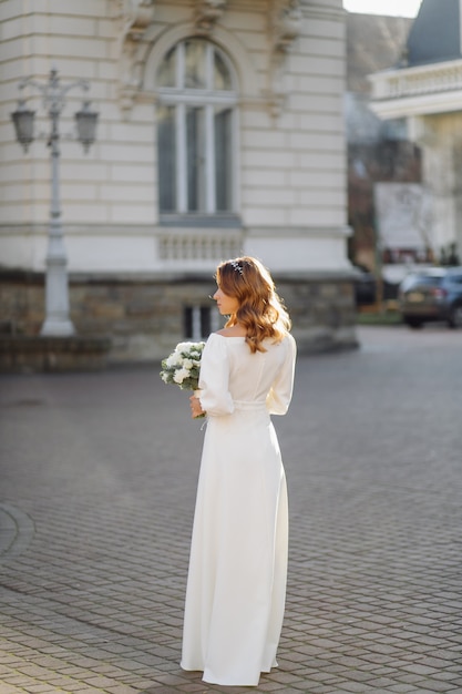 Mulher jovem e bonita no vestido de casamento, posando na rua na cidade