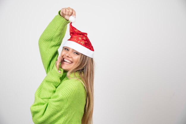 Mulher jovem e bonita posando com chapéu vermelho de Papai Noel.