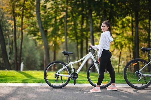 Mulher jovem e bonita posando para uma bicicleta branca