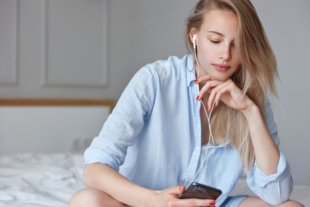 Mulher jovem e bonita relaxando na cama e ouvindo música