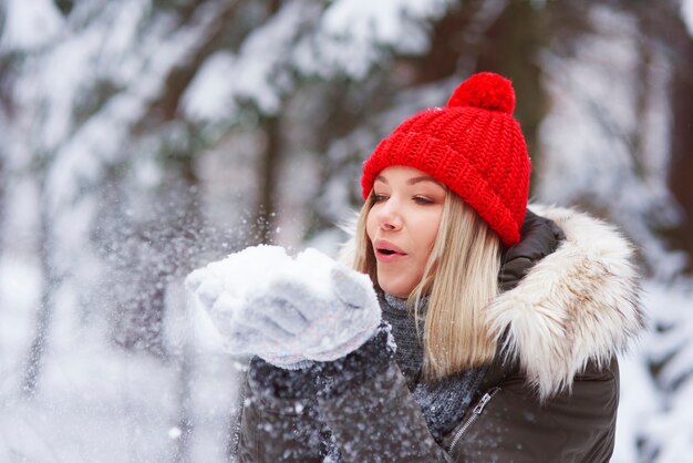 Mulher jovem e bonita soprando flocos de neve