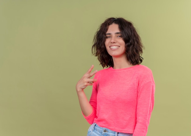 Mulher jovem e bonita sorridente mostrando três em uma parede verde isolada com espaço de cópia