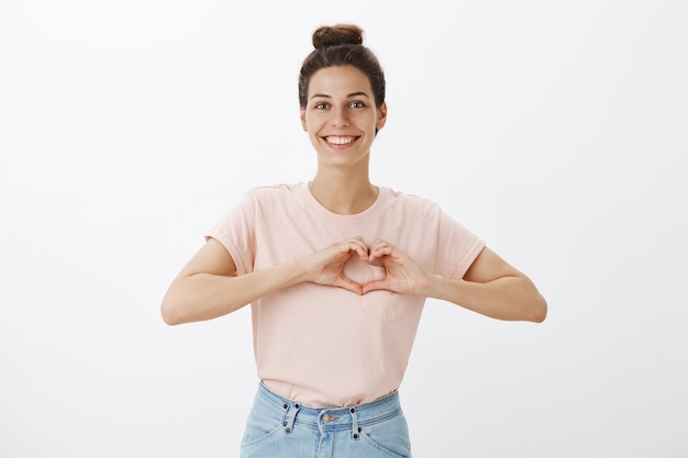 Mulher jovem e bonita sorridente posando contra a parede branca