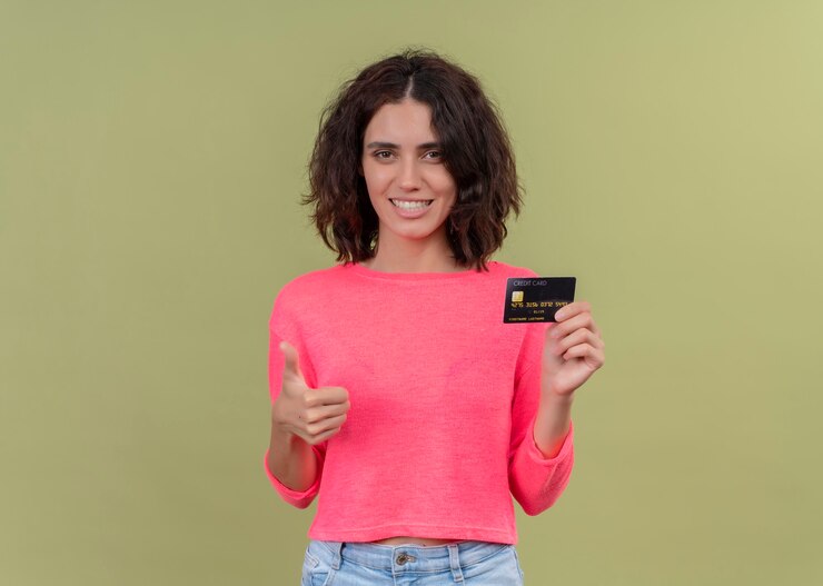 Foto grátis mulher jovem e bonita sorridente segurando um cartão e mostrando o polegar na parede verde isolada