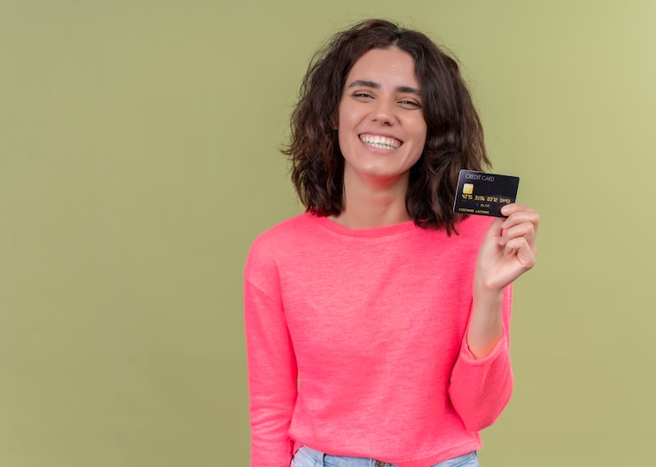 Foto grátis mulher jovem e bonita sorridente segurando um cartão na parede verde isolada com espaço de cópia