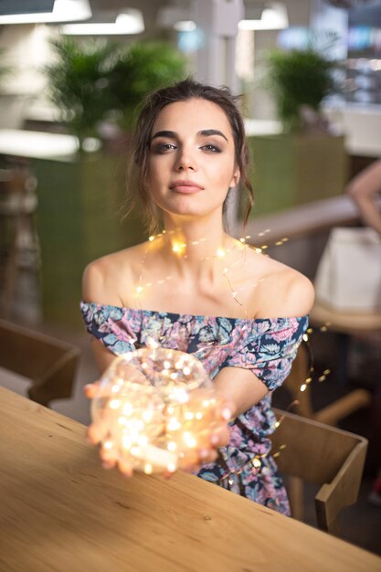 Foto grátis mulher jovem e bonita sorrindo e falando guirlandas de luzes na cidade