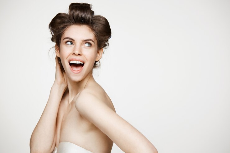 Foto grátis mulher jovem e bonita surpresa em rolos de cabelo, sorrindo com a boca aberta. conceito de beleza e spa.