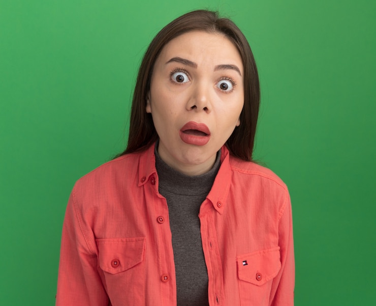 Foto grátis mulher jovem e bonita surpresa olhando para a frente, isolada na parede verde