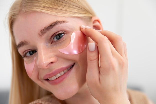 Foto grátis mulher jovem e bonita usando um produto para o rosto