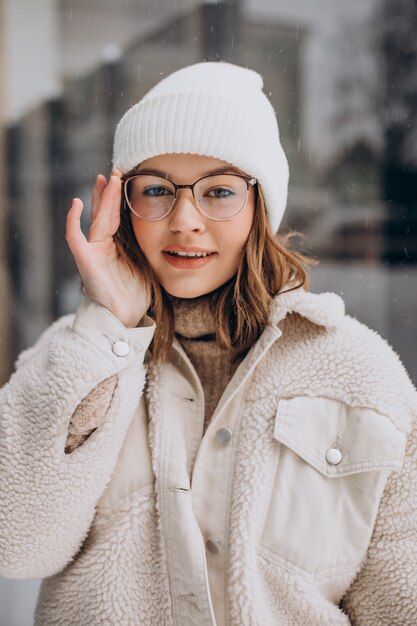 Mulher jovem e bonita vestida de bege andando na rua no inverno