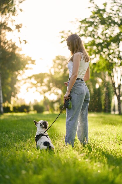 Mulher jovem e buldogue francês no parque