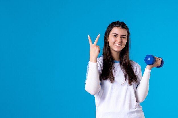 Mulher jovem e feliz de frente segurando halteres azuis