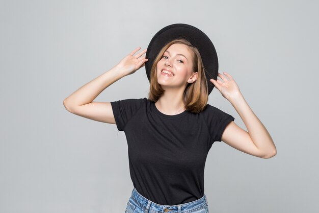 Mulher jovem e linda com chapéu preto e flexível posando isolado no branco