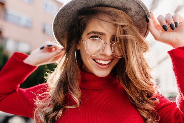 Mulher jovem e linda com sorriso sincero, posando de óculos em um dia ensolarado de outono