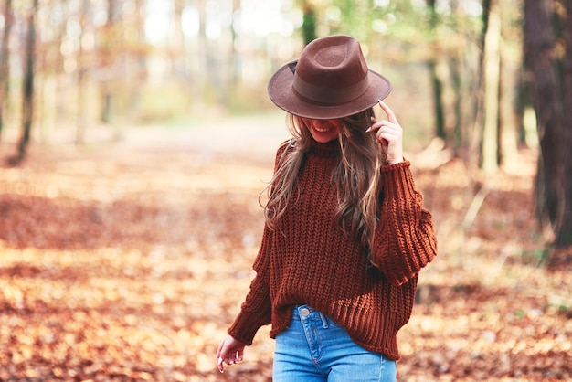 Mulher jovem e linda usando roupas quentes na floresta de outono