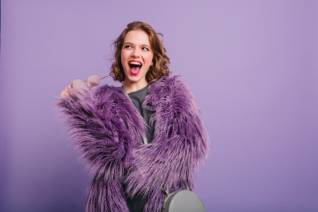 Mulher jovem e maravilhosa com um sorriso feliz posando em um fundo roxo brilhante