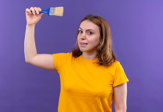 Foto grátis mulher jovem e sorridente casual levantando o pincel no espaço roxo isolado