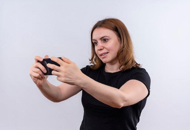 Mulher jovem e sorridente casual segurando e olhando para o celular em um espaço em branco isolado