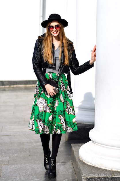 Mulher jovem elegante andando na rua com jaqueta de couro e saia floral