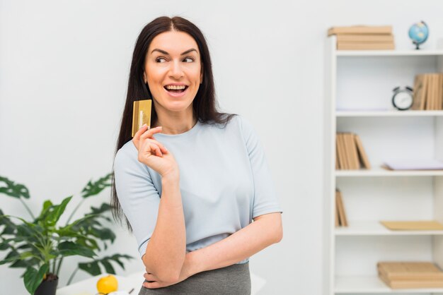 Mulher jovem, em, azul, ficar, com, cartão crédito, em, escritório