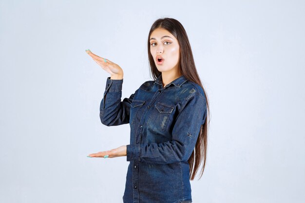 Foto grátis mulher jovem em camisa jeans mostrando as medidas de um produto