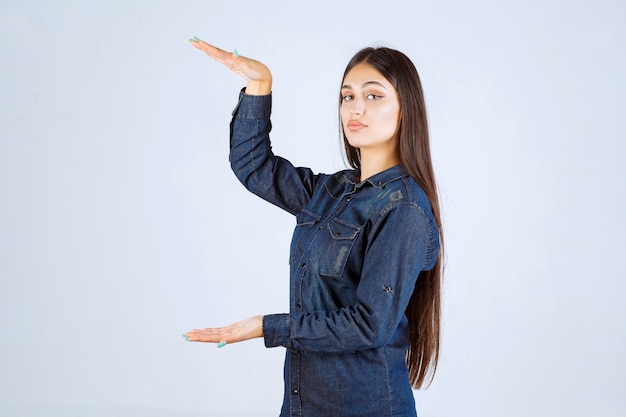 Mulher jovem em camisa jeans mostrando as medidas de um produto