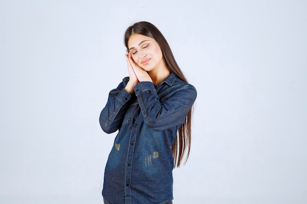 Mulher jovem em camisa jeans parece exausta e com sono