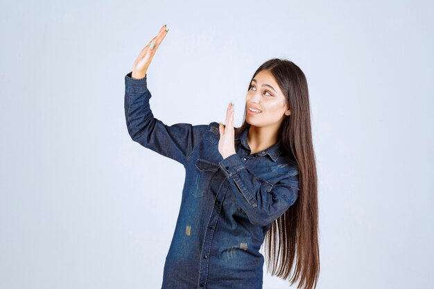 Mulher jovem em camisa jeans tentando prevenir e impedir algo